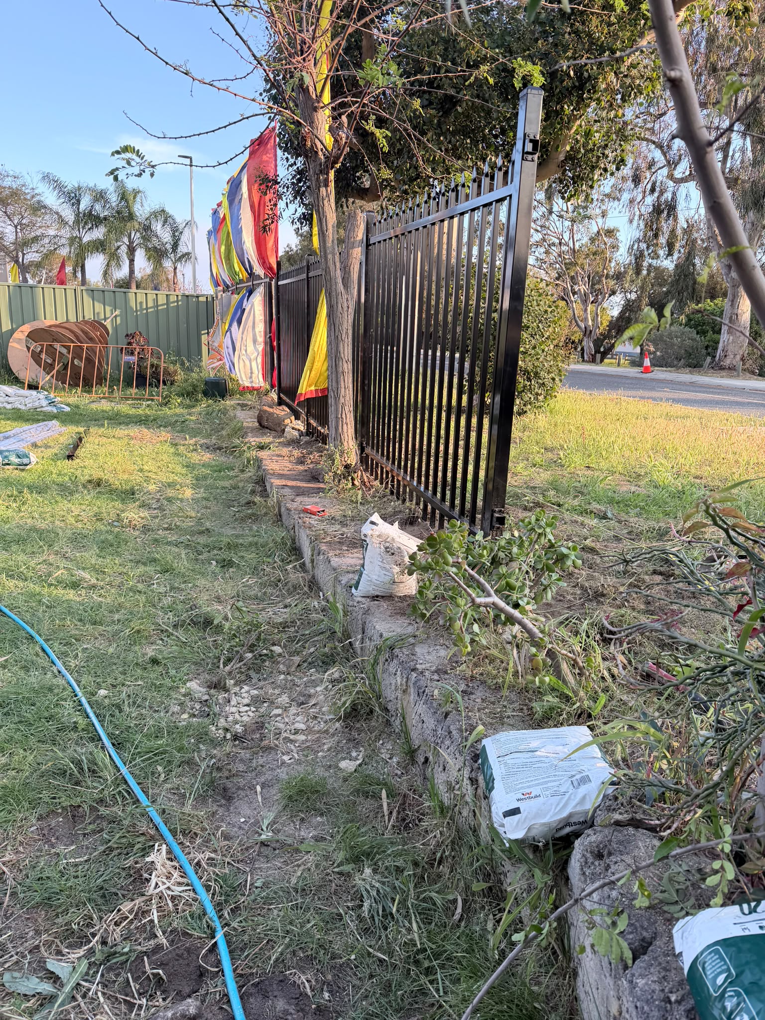 Garrison fencing installation beside established trees and vegetation in Wanneroo